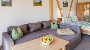 Ein gemütliches Zimmer mit einer Couch, einem Bett, einem Tisch mit Obst und Holzbalken.