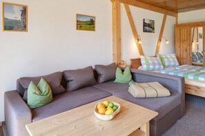 Una camera accogliente con divano, letto, tavolo con frutta e travi in legno.