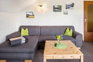 Una sala de estar moderna con un sofá seccional gris, una mesa de centro de madera y obras de arte colgadas en la pared.