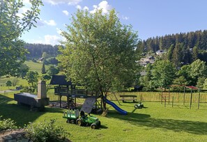 En legeplads med rutschebane, klatrestruktur og en grøn traktor.