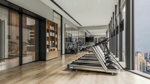 Un gimnasio moderno con cintas de correr, equipo de ejercicio y vistas a la ciudad.
