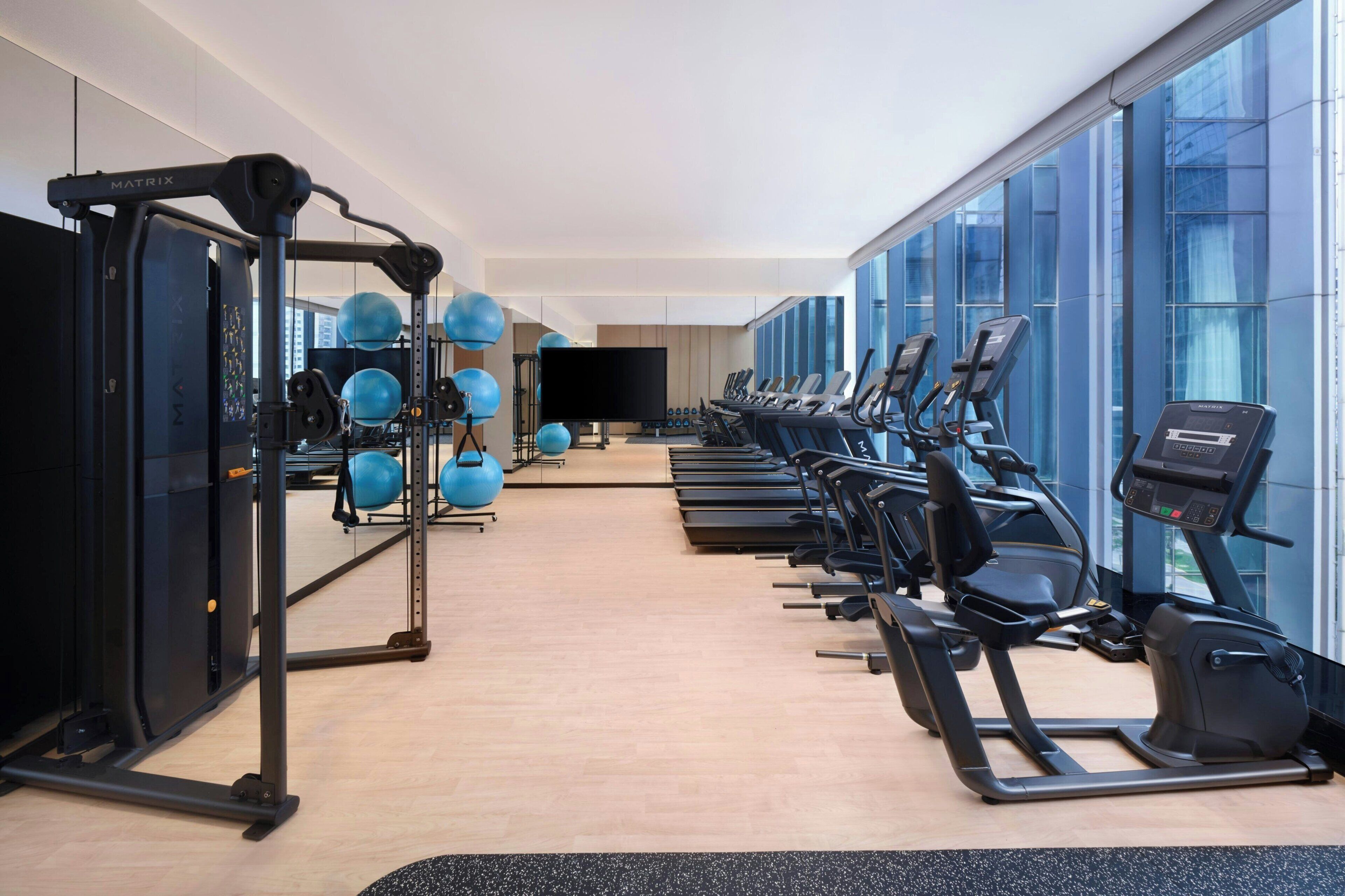 Una palestra con attrezzi per l'allenamento, una televisione e ampie finestre.
