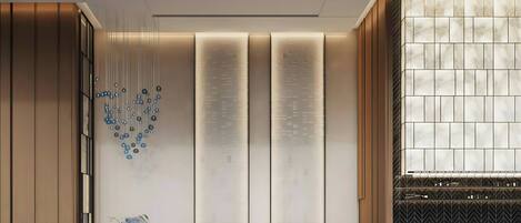 Un área de recepción moderna con una mesa de recepción, un muro decorativo con una escultura de ola y paneles de luz verticales.