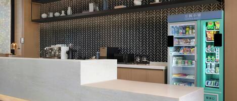 Un espace d’accueil moderne avec un comptoir de réception blanc, un distributeur automatique et un mur décoré de motifs.
