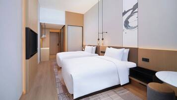 Een moderne hotelkamer met een groot bed, nachtkastjes, een flatscreen televisie en een groot kunstwerk aan de muur.