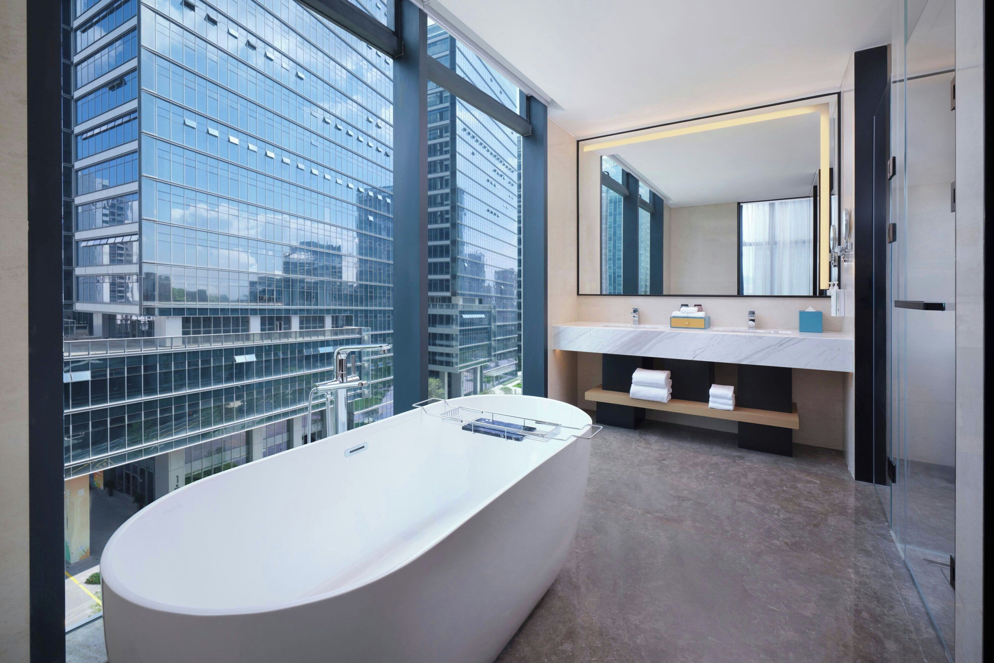 A modern bathroom with a large bathtub, a dual sink vanity, and a large mirror.