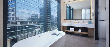 A modern bathroom with a large bathtub, a dual sink vanity, and a large mirror.