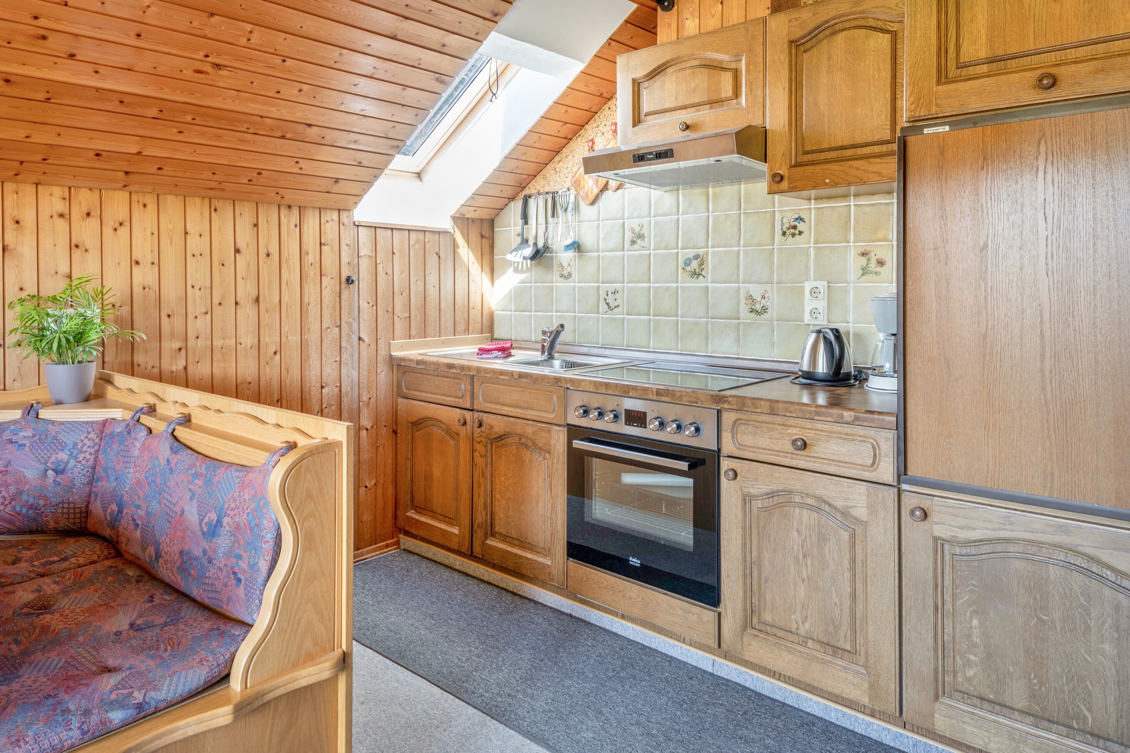 A kitchen with wooden cabinets, a built-in oven, a sink, and a window above the countertop.