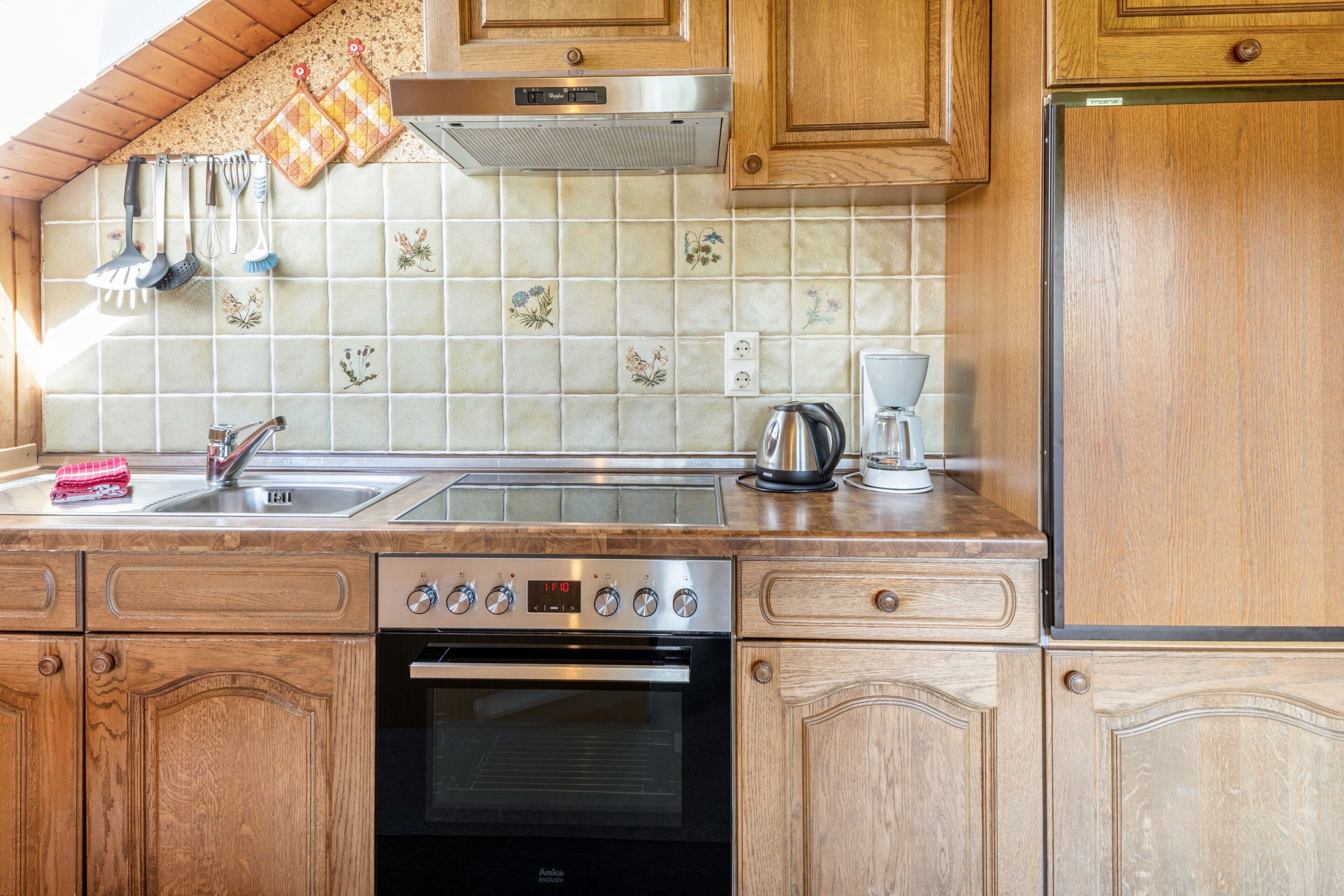 A kitchen with wooden cabinets, a stainless steel oven, a coffee maker, and a tiled backsplash.