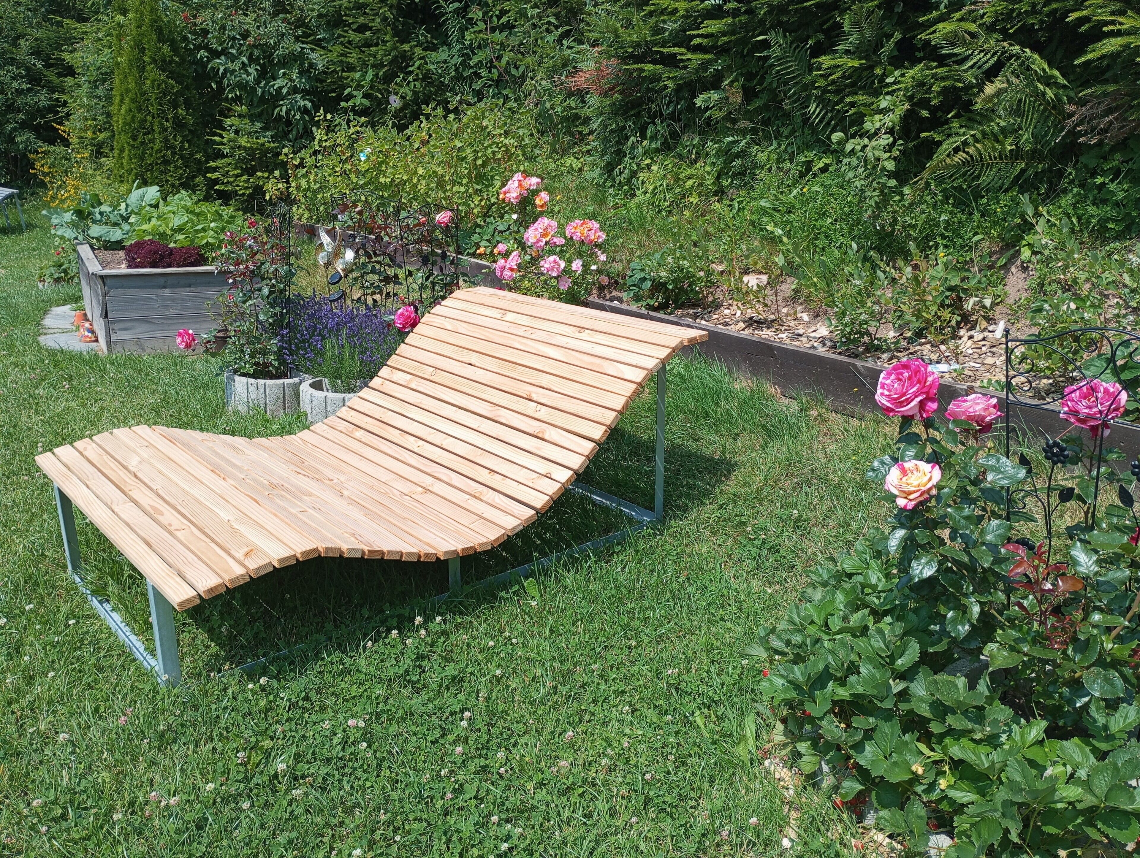 A wooden bench in a garden with various plants and flowers.