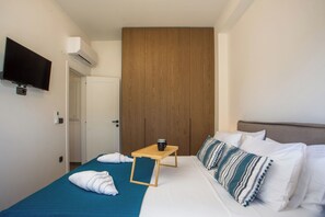 A hotel room with a bed, a wooden wardrobe, a TV mounted on the wall, and a small table with a cup. - Escape to Casadi Fileri Villa, a brand-new property in the area of Ialysos. (Rhodes)