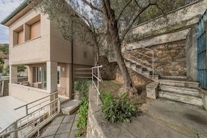 Un edifici modern amb una escala de pedra, un arbre i una barana metàl·lica.