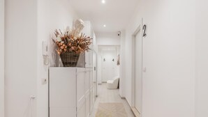 A hallway with a white door labeled '2', a white reception desk, and a decorative plant.