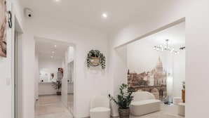A modern living room with a sofa, a potted plant, and a wall mural of a cityscape.