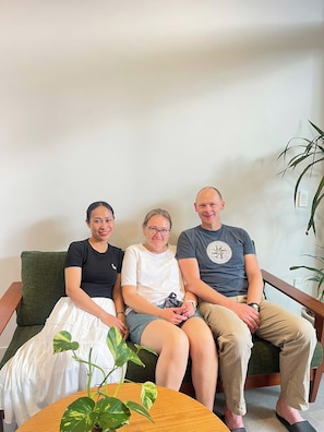 Three people seated on a sofa with a potted plant on a wooden table in front. - Madam Thu House (Hue)
