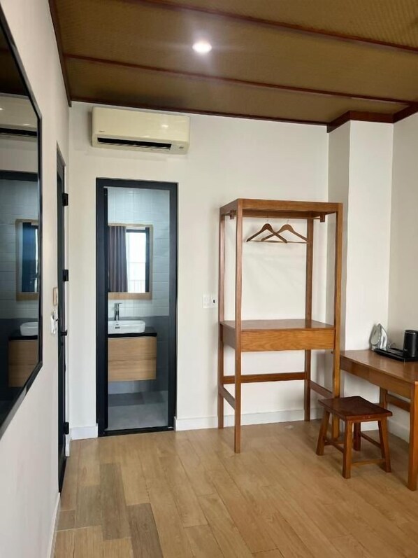 A room with a wooden bunk bed, a desk with a chair, a mirror, and an air conditioning unit. - Madam Thu House (Hue)