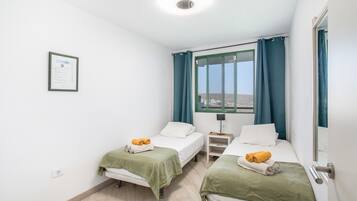 Ein Hotelzimmer mit zwei Betten, einem Nachttisch, einem Fenster mit Vorhängen und einem gerahmten Zertifikat an der Wand.