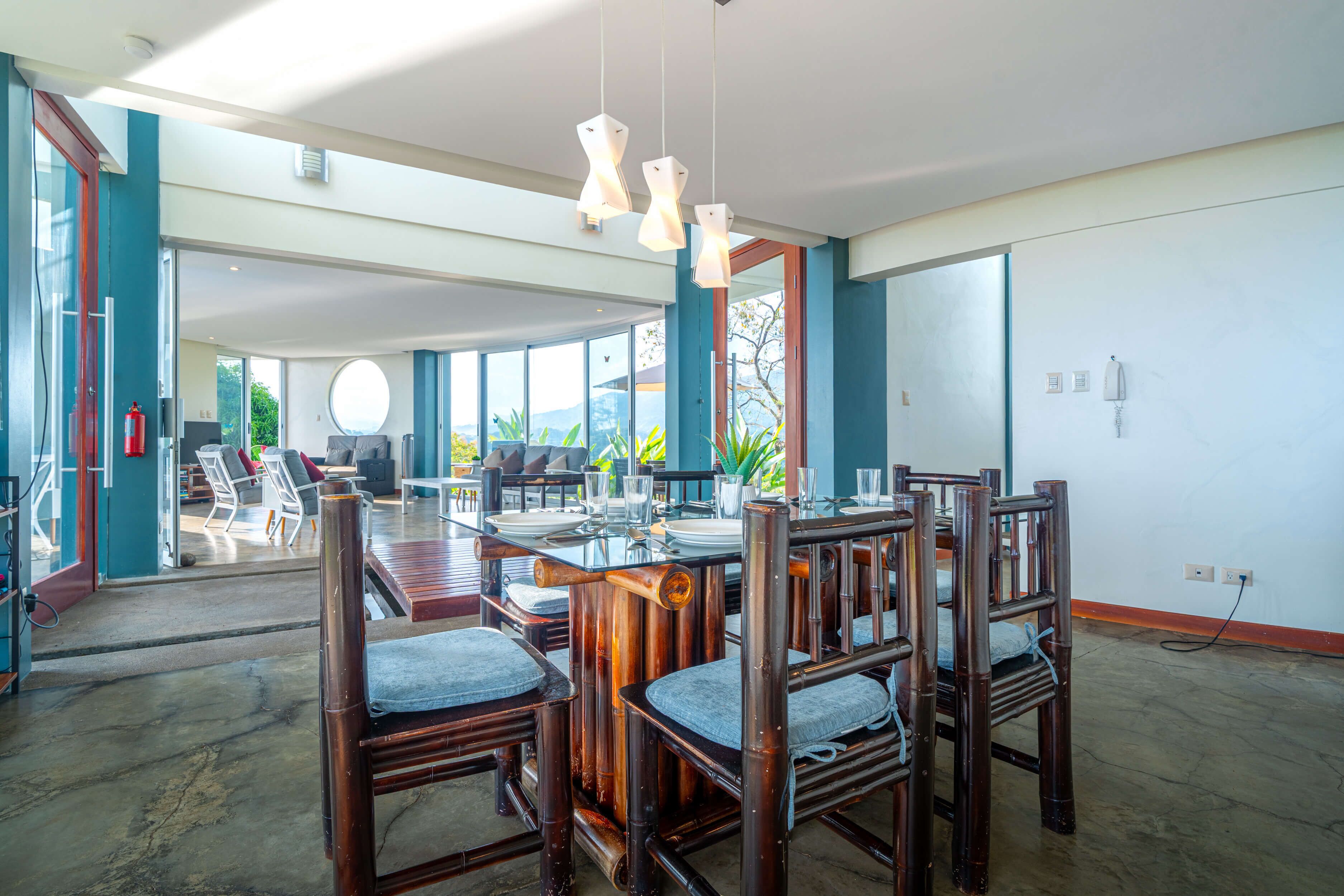 A spacious dining area with a high ceiling, large windows, and a view of the outdoors.