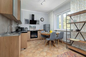 Une cuisine moderne avec des meubles en bois, un four encastré et un coin repas comprenant une table et des chaises.
