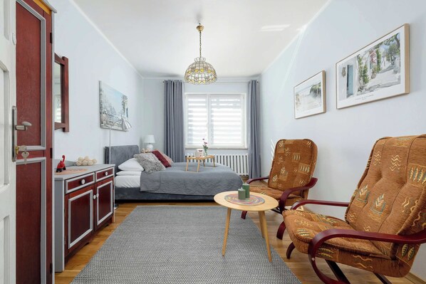 A bedroom with a bed, bedside table, lamp, and a window with curtains.