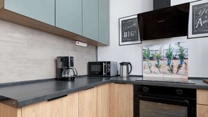 Eine moderne Küche mit Mikrowelle, Kaffeemaschine und Backofen. An den Wänden hängen Bilder in Rahmen.