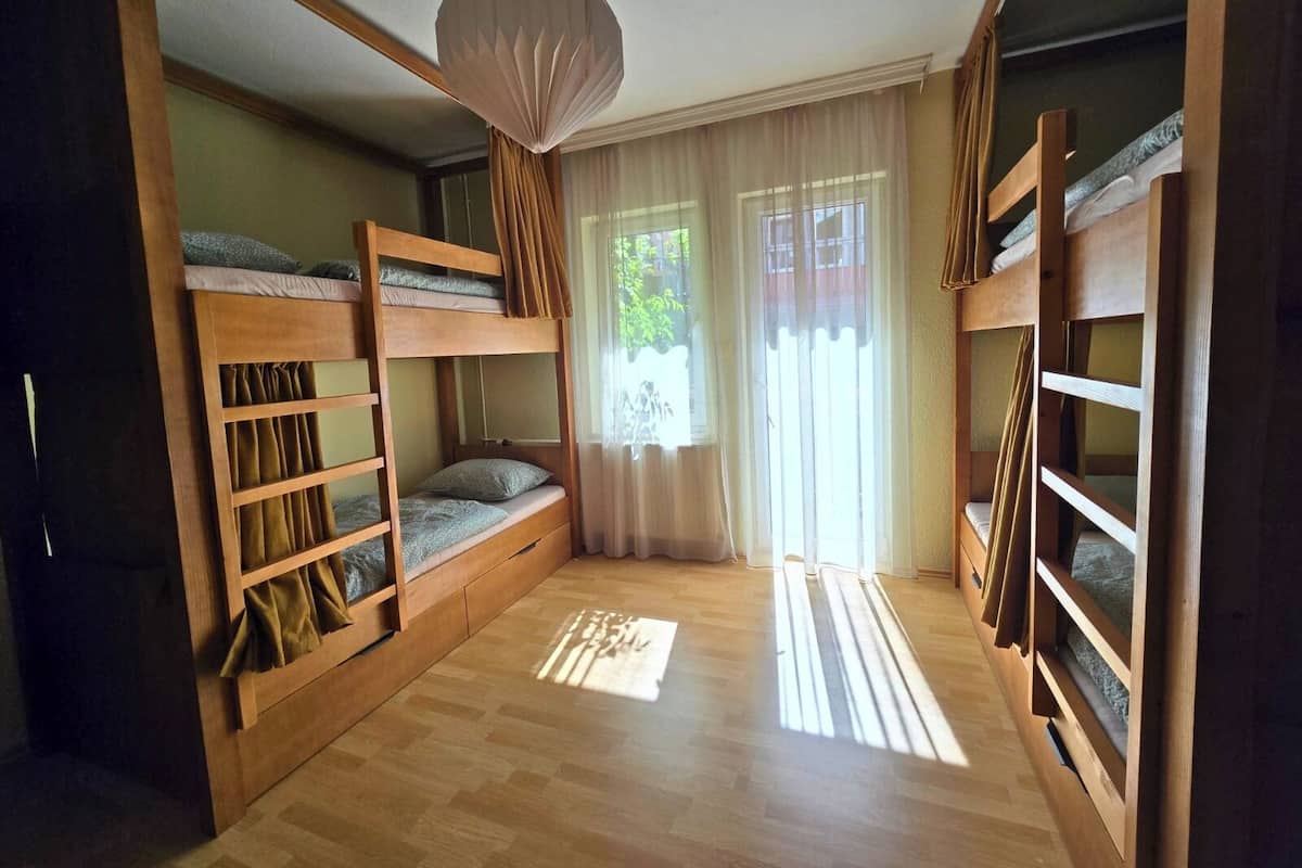 Una habitación con literas, una lámpara colgante y una ventana con cortinas.