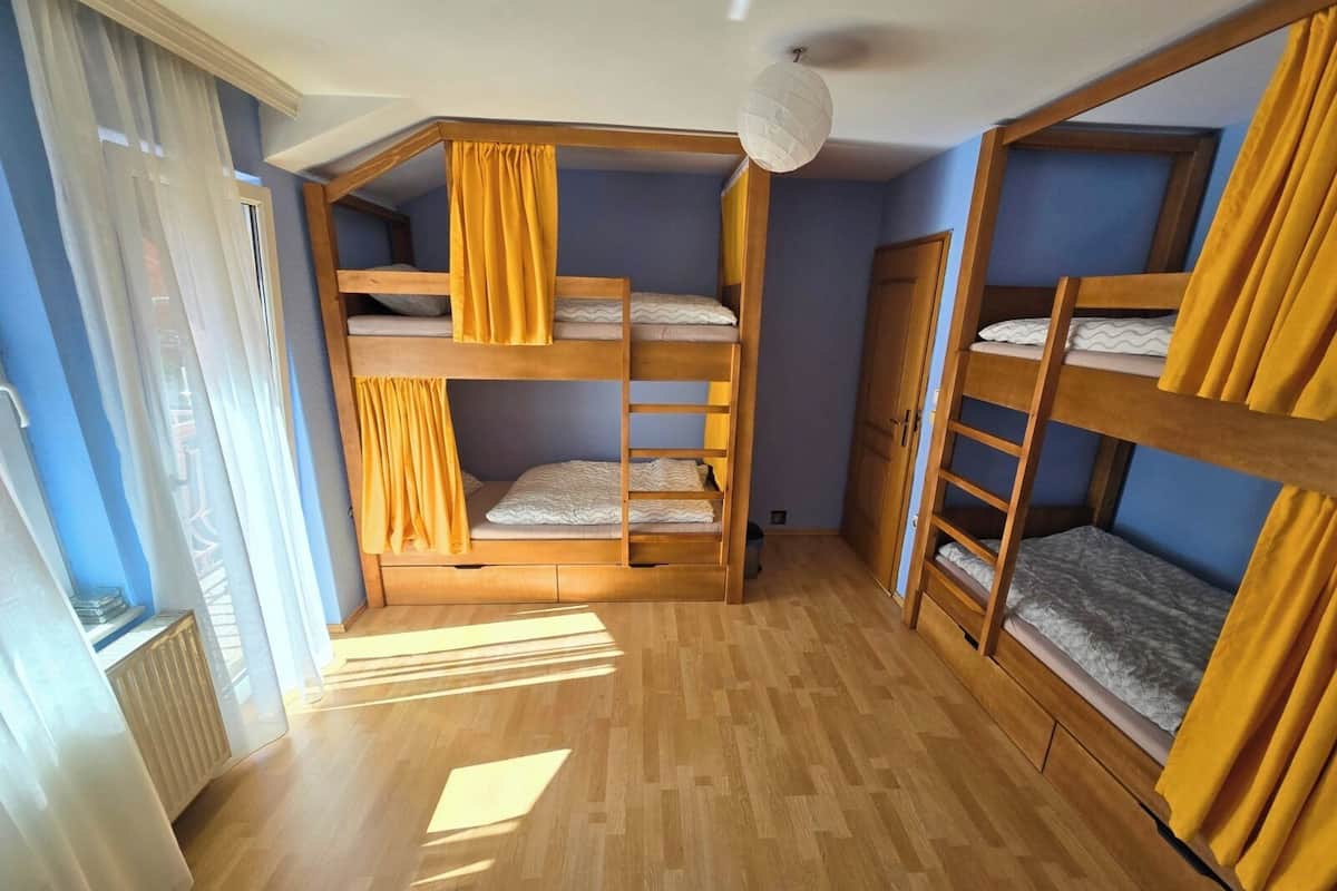 Una habitación con literas, suelo de madera y cortinas.
