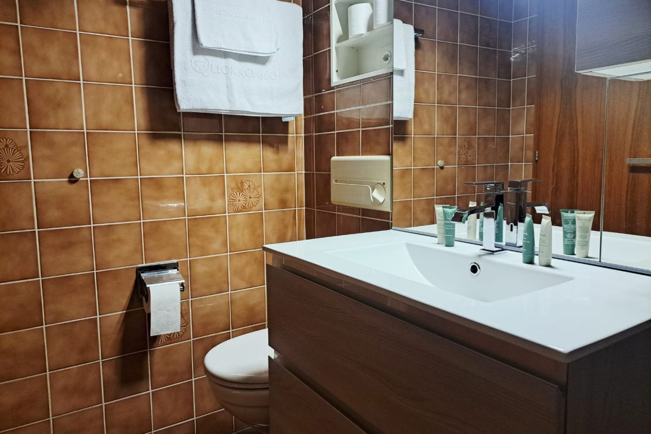 Une salle de bain avec un lavabo blanc, un miroir et un porte-serviettes.