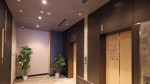 A modern elevator with floor labels and a potted plant in the hallway. - Dormy Inn Komatsu Heihou-no-Yu (Komatsu)