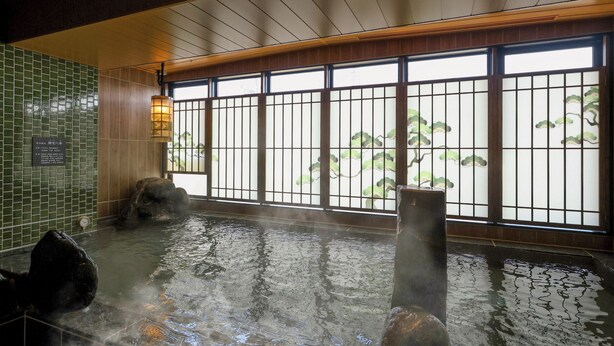 A hot spring bath with a view of a traditional Japanese screen, a stone lantern, and a tiled wall. - Dormy Inn Komatsu Heihou-no-Yu (Komatsu)