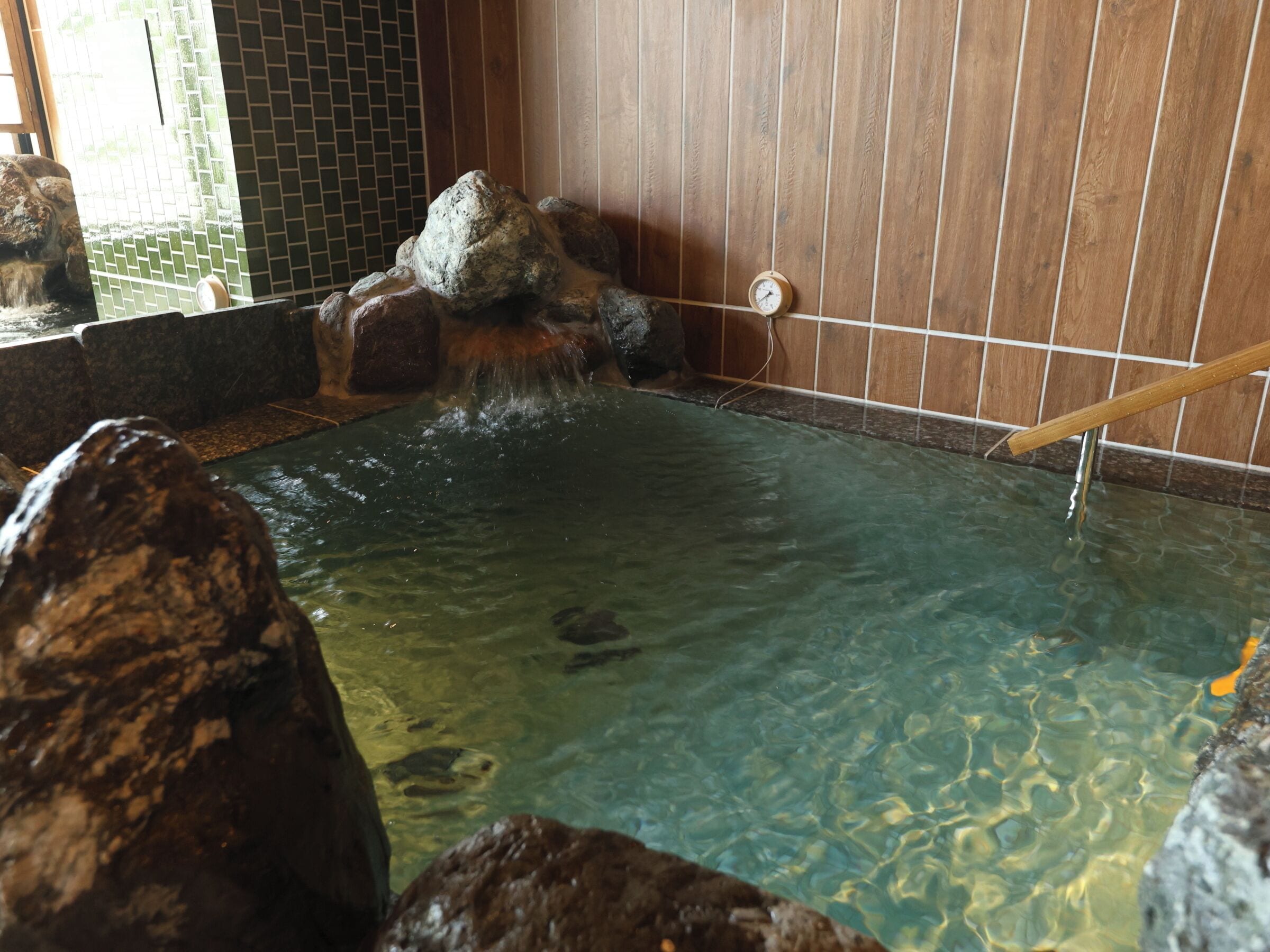 A hot spring area with clear water, wooden walls, and a wooden ladder.