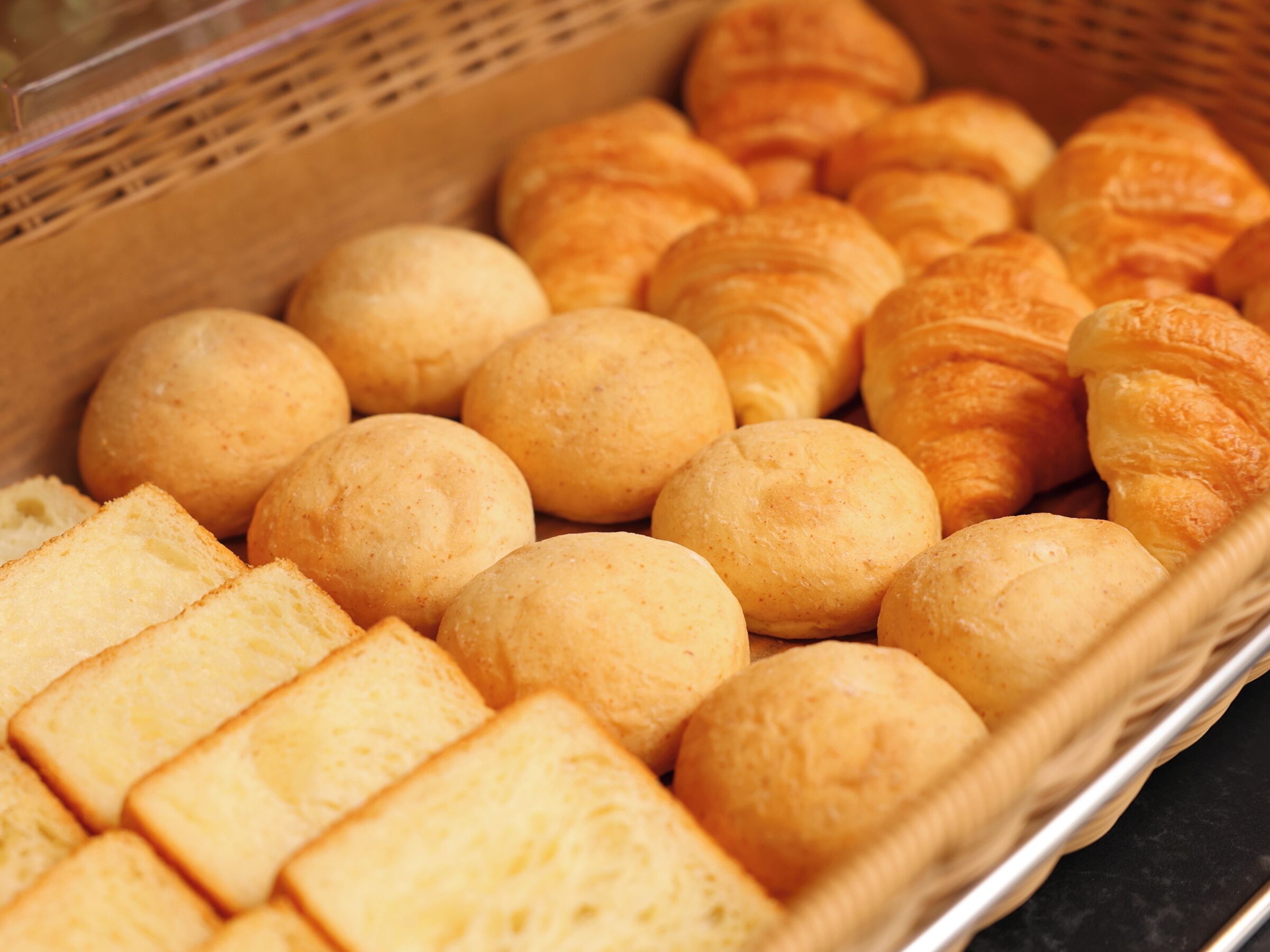 A basket containing various baked goods, including round bread rolls and rectangular slices.