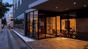 A modern hotel entrance with glass doors, a covered outdoor area, and a visible sign for the DMRY HOTEL. - Dormy Inn Komatsu Heihou-no-Yu (Komatsu)