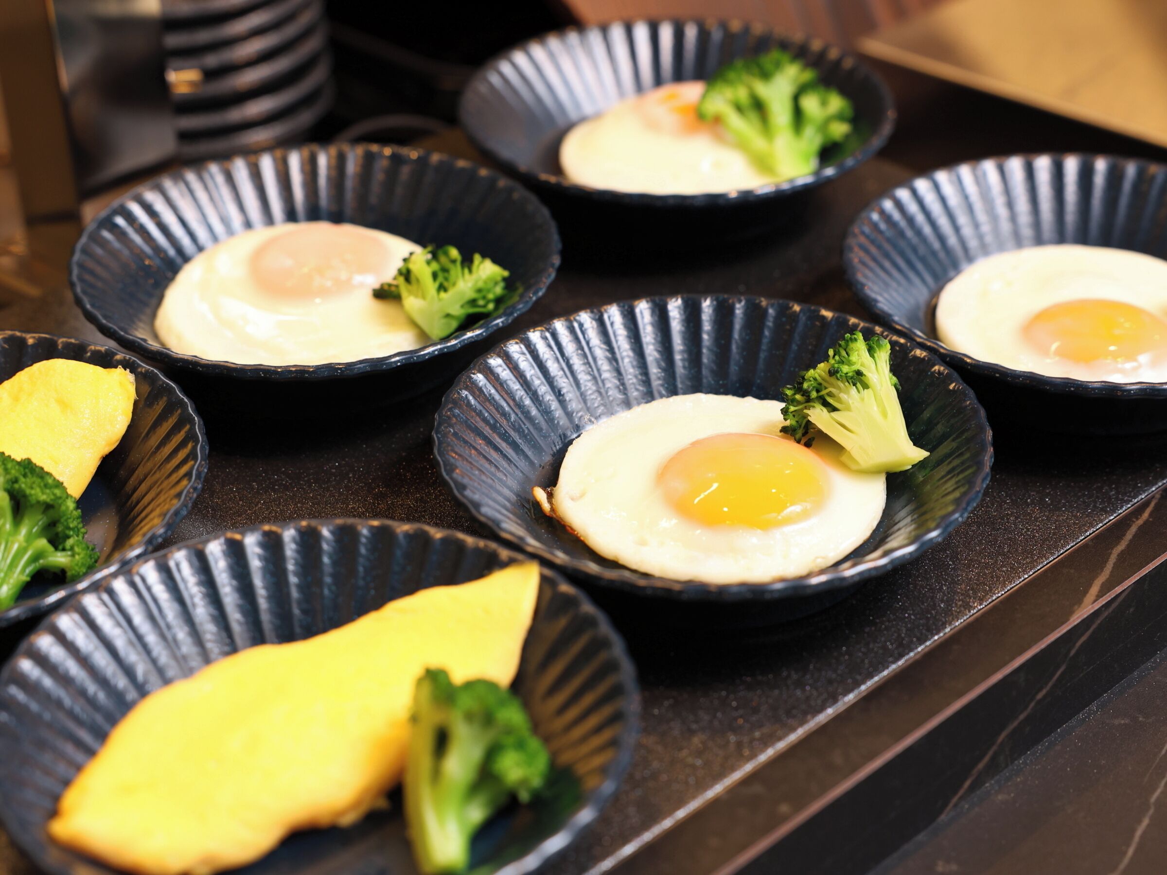 A series of bowls with eggs and broccoli on a countertop.