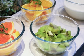 Tres tazones de vidrio con frutas cortadas sobre una superficie blanca.