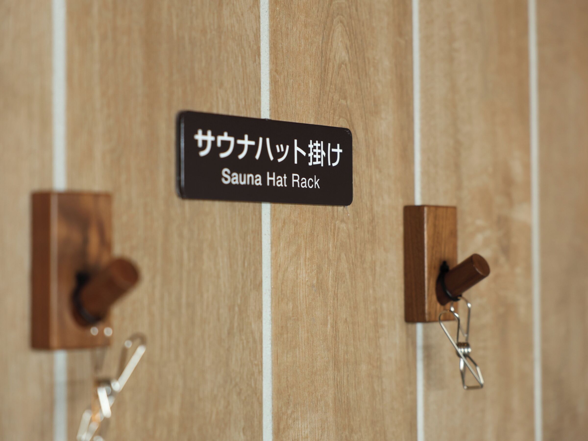 A wooden wall with a sign indicating a sauna hat rack.