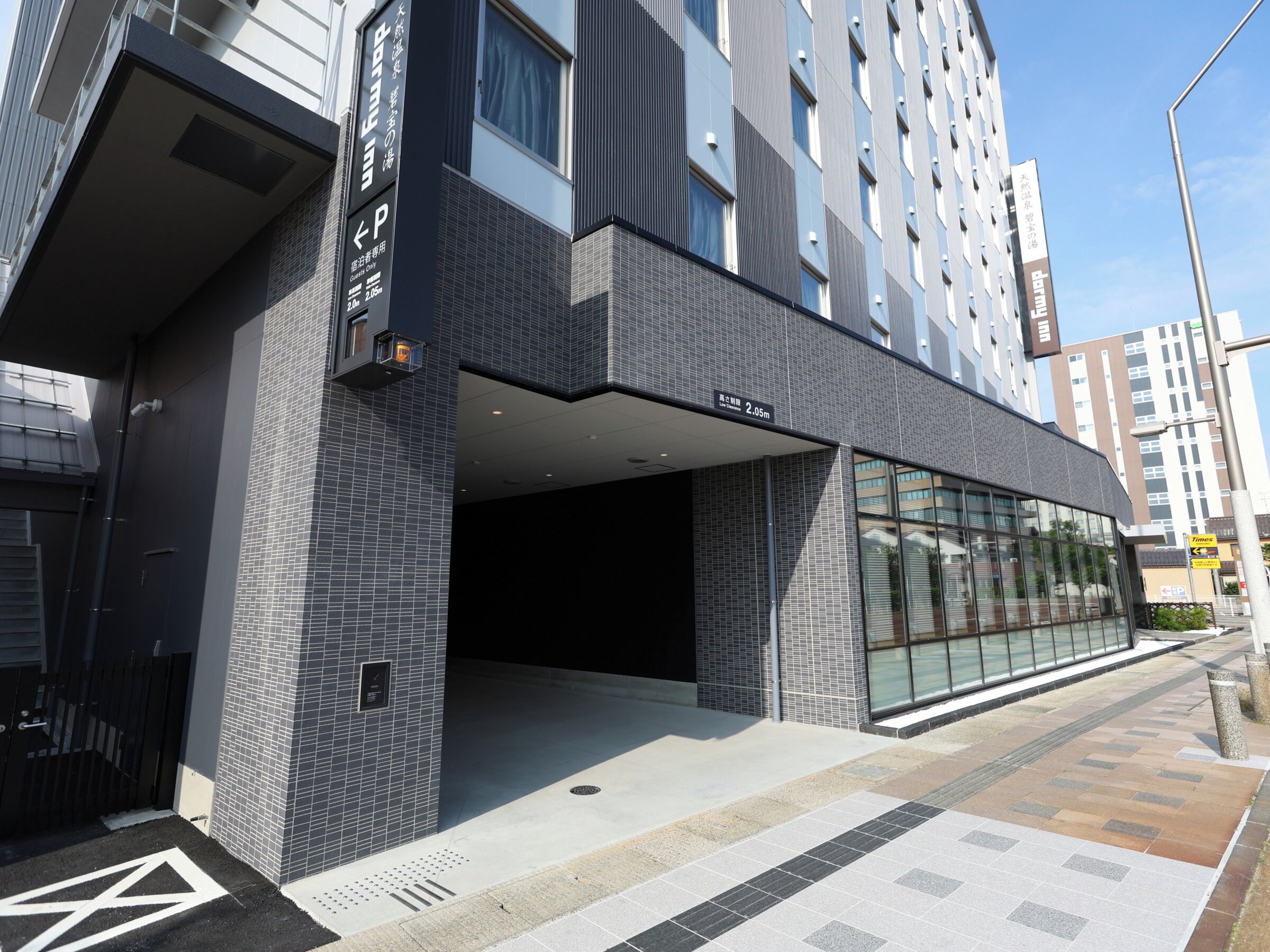 A modern building with a covered entrance, a clear pathway, and a visible sign indicating a height of 2.05m.