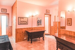 Una habitación con paneles de madera, un aparador de madera, una mesa y obras de arte en la pared.