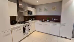 A modern kitchen with white cabinetry, a stove, and a microwave. - Luxury Belfast City Centre Apartment with Views (Belfast)