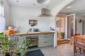A kitchen with a central island, a dining area with a table, and a view of the outside.