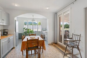 Una cocina con una mesa de comedor, sillas, una máquina de café y una planta.