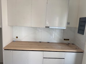 Eine Küche mit weißen Schränken, einer Holz Arbeitsplatte und einer Spritzschutzleiste mit marmorähnlichem Muster.
