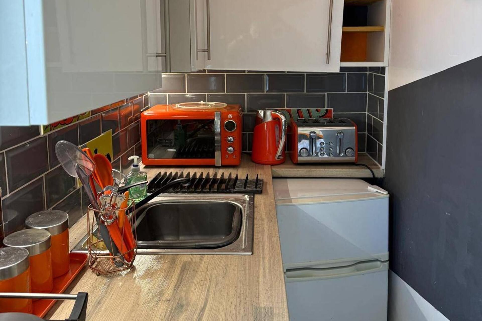 A compact kitchen with a microwave, toaster, and sink.