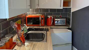 A compact kitchen with a microwave, toaster, and sink.