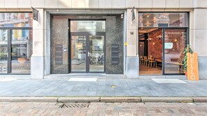 Un edificio con puerta de acceso de vidrio, un letrero que dice 'BELGA & CO. SIMPLE PLEASURES' y un letrero que dice 'HELLO'.
