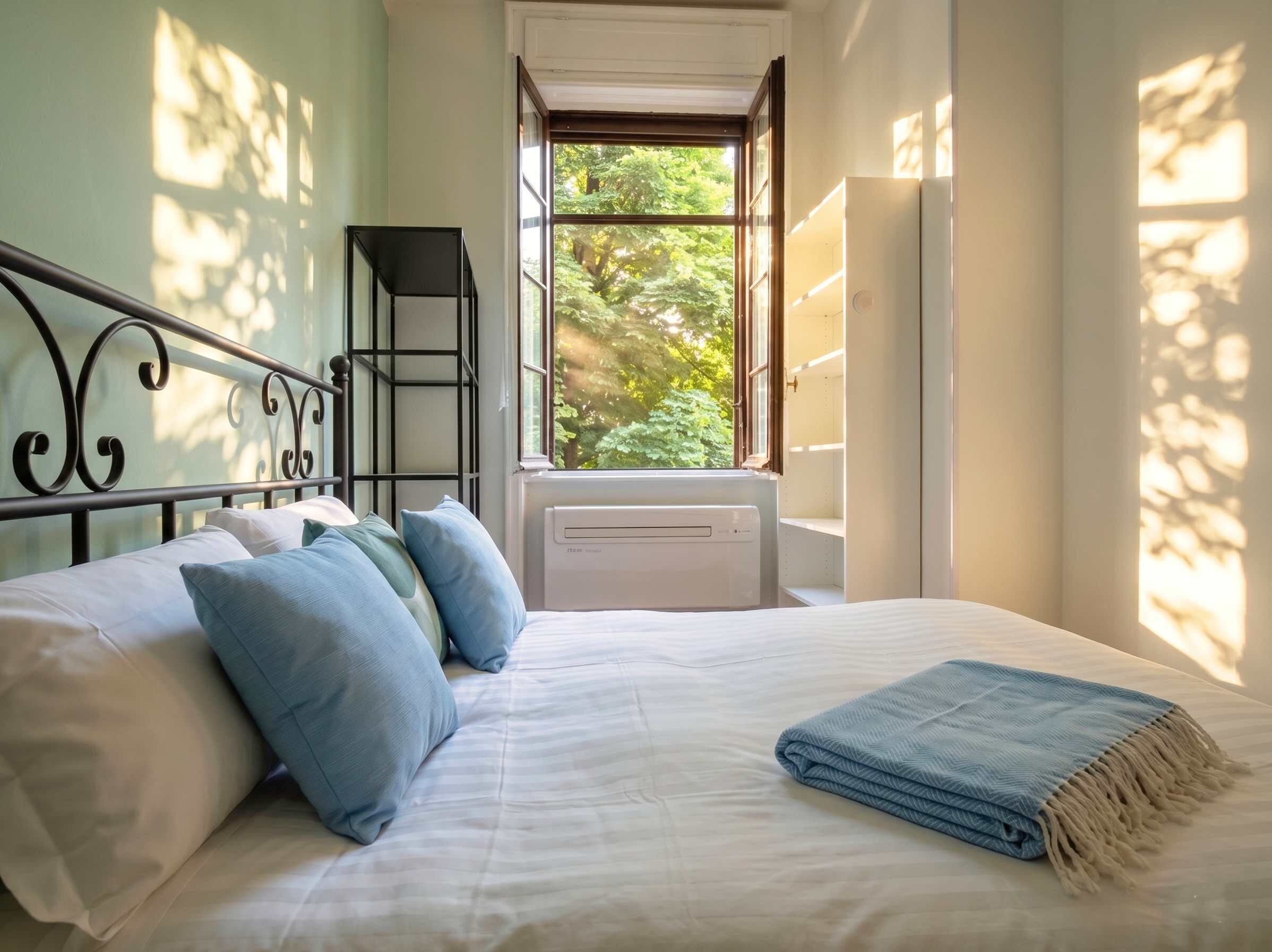 Une chambre à coucher avec un lit, des oreillers, une fenêtre et un radiateur.