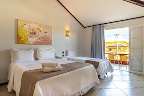 A hotel room with two beds, a painting on the wall, a balcony with a view, and a table with chairs. - Suri Búzios Hotel (Búzios)