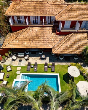 Uma casa grande com telhado de cerâmica, piscina e área de estar externa.