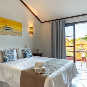 Ein Hotelzimmer mit einem Bett, einem Gemälde, einem Nachttisch und Blick ins Freie.