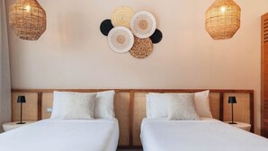 Una camera d'albergo con due letti, una testiera in rattan e due lampade a parete.